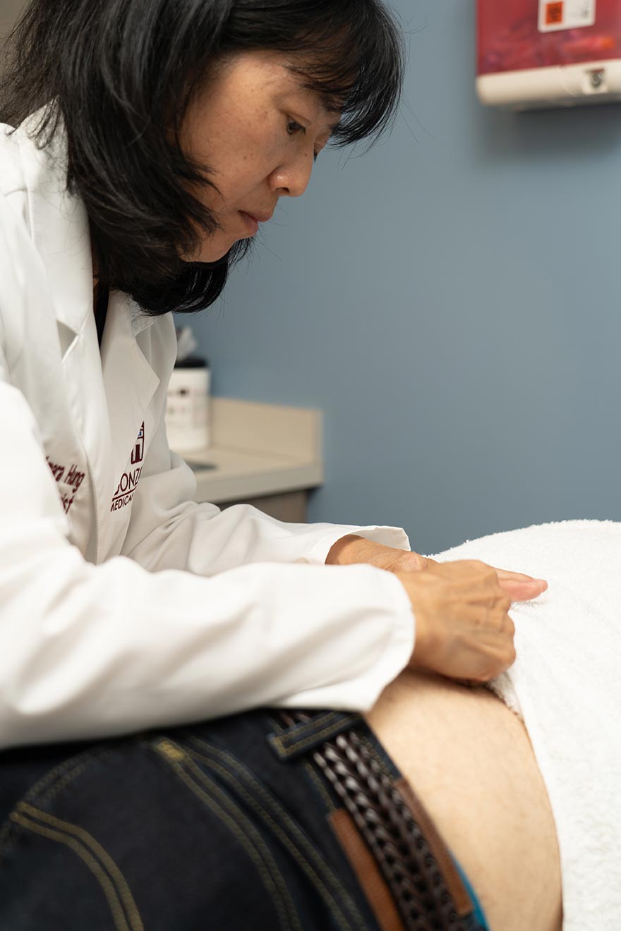 Dr. Hung is seen administering a treatment on the back of a patient.